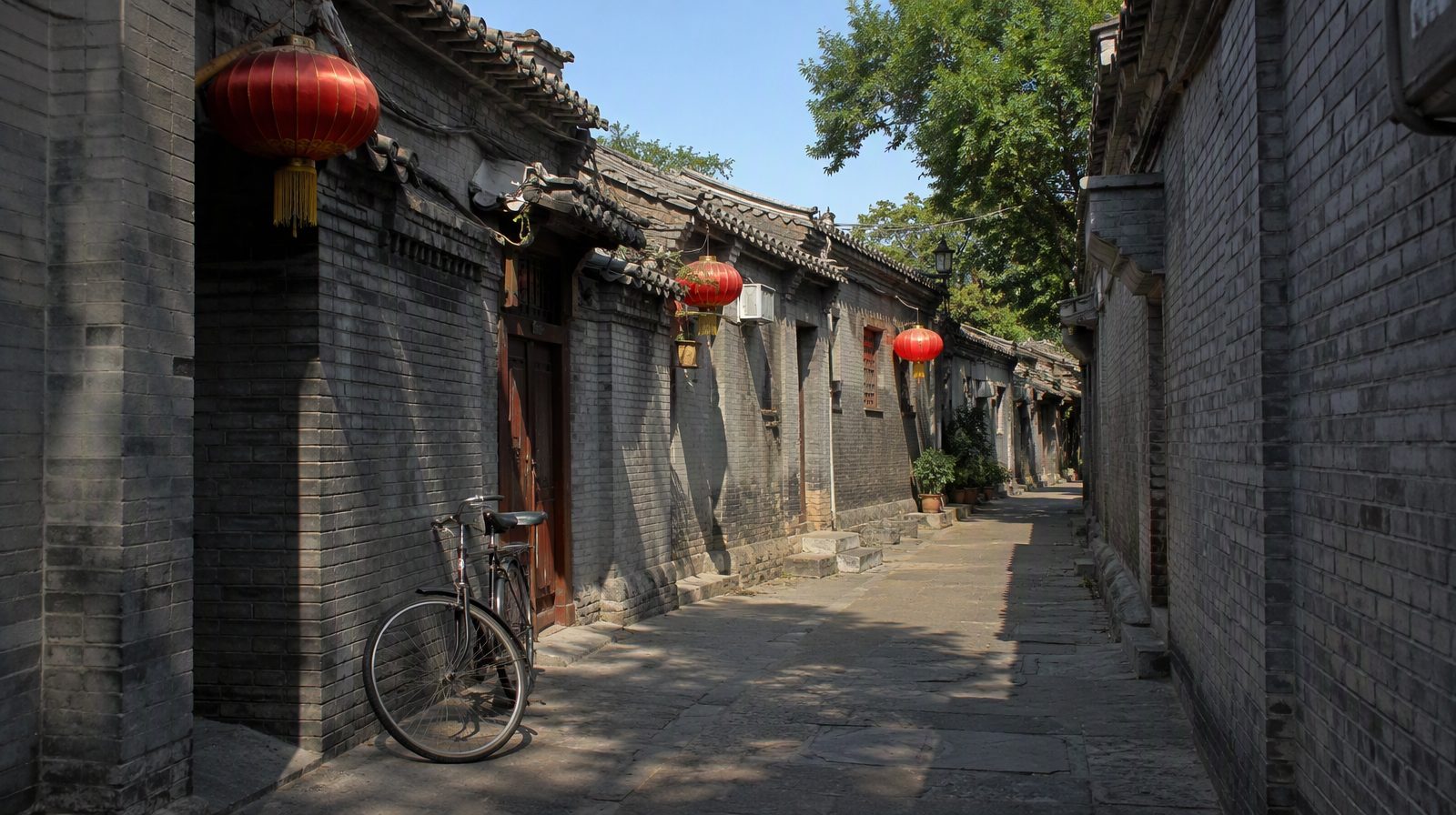 A hutong alley in Beijing with grey brick walls and red lanterns